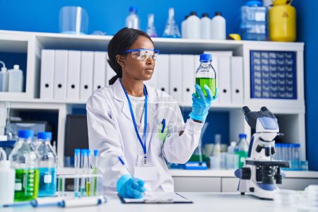 Photo for Young african american woman scientist measuring liquid at laboratory - Royalty Free Image