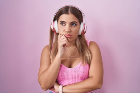 Photo for Young blonde woman listening to music using headphones thinking looking tired and bored with depression problems with crossed arms. - Royalty Free Image
