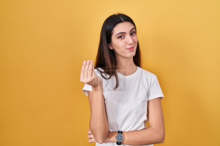Photo for Young beautiful woman standing over yellow background doing italian gesture with hand and fingers confident expression - Royalty Free Image