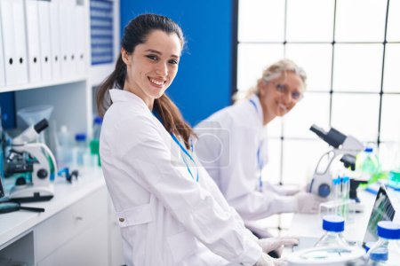 Photo for Two women scientists using microscope working at laboratory - Royalty Free Image