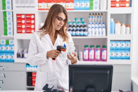 Foto de Young woman pharmacist scanning pills bottle at pharmacy - Imagen libre de derechos