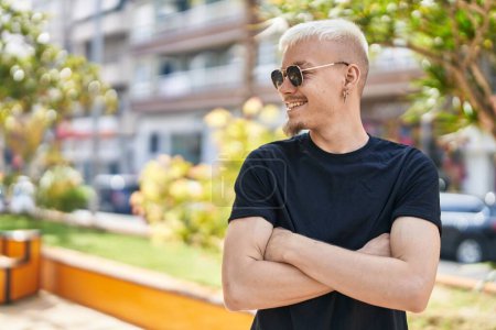Téléchargez les photos : Jeune homme caucasien souriant confiant debout avec les bras croisés geste au parc - en image libre de droit