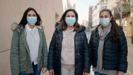 Photo for Mother and daugthers wearing medical mask standing together at street - Royalty Free Image