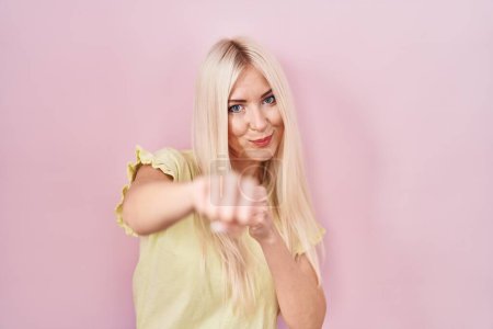Photo for Caucasian woman standing over pink background punching fist to fight, aggressive and angry attack, threat and violence - Royalty Free Image