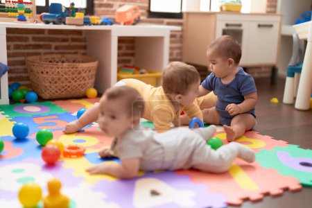 Foto de Grupo de niños pequeños que juegan con juguetes arrastrándose por el suelo en el jardín de infantes - Imagen libre de derechos