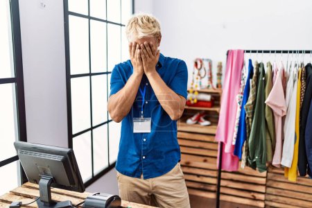 Photo for Young blond man working as manager at retail boutique with sad expression covering face with hands while crying. depression concept. - Royalty Free Image