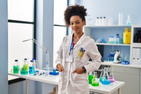 Photo for Young african american woman wearing scientist uniform standing at laboratory - Royalty Free Image