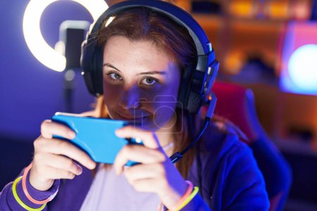 Photo for Young beautiful plus size woman streamer playing video game using smartphone at gaming room - Royalty Free Image