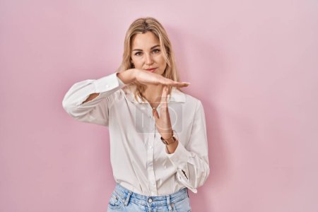 Photo for Young caucasian woman wearing casual white shirt over pink background doing time out gesture with hands, frustrated and serious face - Royalty Free Image