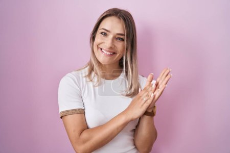 Photo for Blonde caucasian woman standing over pink background clapping and applauding happy and joyful, smiling proud hands together - Royalty Free Image