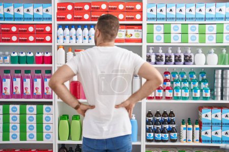 Téléchargez les photos : Jeune homme caucasien client regardant étagères à la pharmacie - en image libre de droit