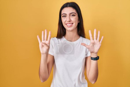 Photo for Young beautiful woman standing over yellow background showing and pointing up with fingers number nine while smiling confident and happy. - Royalty Free Image