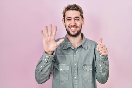 Téléchargez les photos : Hispanic man with beard standing over pink background showing and pointing up with fingers number six while smiling confident and happy. - en image libre de droit