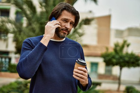 Foto de Hombre guapo de mediana edad hablando por teléfono al aire libre en el parque - Imagen libre de derechos