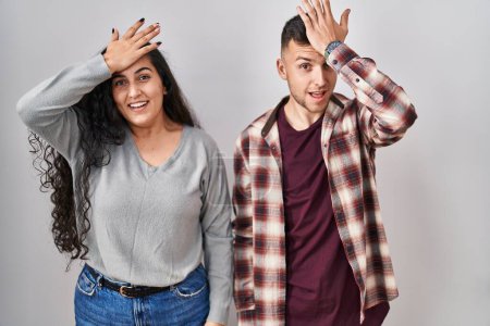 Foto de Young hispanic couple standing over white background surprised with hand on head for mistake, remember error. forgot, bad memory concept. - Imagen libre de derechos