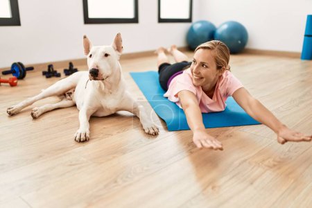 Photo for Young caucasian woman smiling confident stretching with dog at sport center - Royalty Free Image