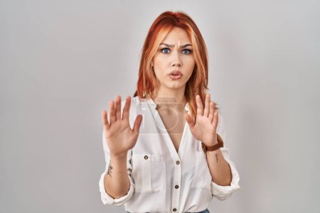 Photo for Young caucasian woman standing over isolated background moving away hands palms showing refusal and denial with afraid and disgusting expression. stop and forbidden. - Royalty Free Image