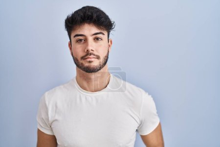 Photo for Hispanic man with beard standing over white background relaxed with serious expression on face. simple and natural looking at the camera. - Royalty Free Image