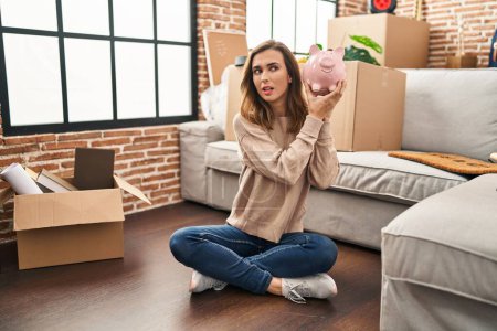 Photo for Young woman holding piggy bank at new home - Royalty Free Image
