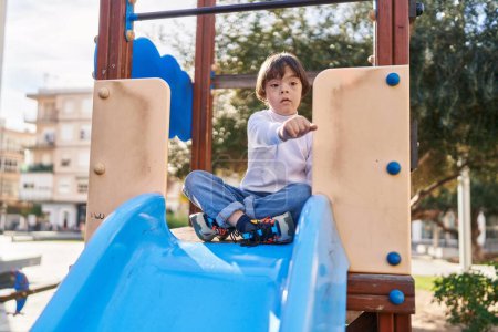 Téléchargez les photos : Enfant trisomique jouant sur la glissière au parc - en image libre de droit