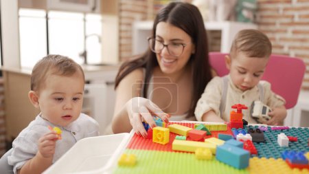 Photo for Teacher and preschool students playing with construction blocks and cars sitting on table at kindergarten - Royalty Free Image