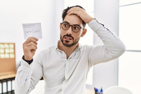 Photo for Young man with beard holding covid record card stressed and frustrated with hand on head, surprised and angry face - Royalty Free Image