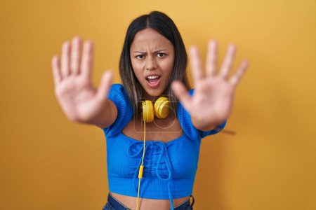 Téléchargez les photos : Jeune femme hispanique debout sur fond jaune faisant geste d'arrêt avec les paumes des mains, expression de colère et de frustration - en image libre de droit