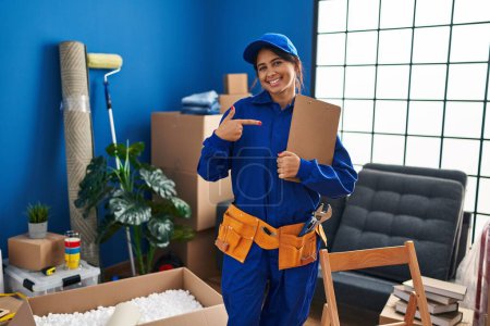 Photo for Young hispanic technician working at house renovation smiling happy pointing with hand and finger - Royalty Free Image