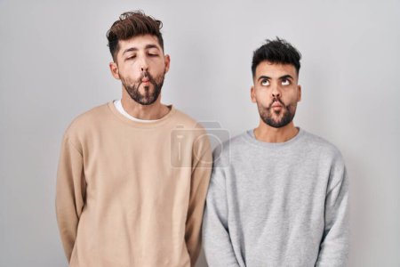 Téléchargez les photos : Young homosexual couple standing over white background making fish face with lips, crazy and comical gesture. funny expression. - en image libre de droit
