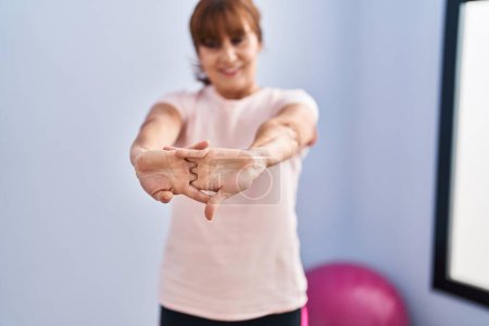 Téléchargez les photos : Middle age woman smiling confident stretching arms at sport center - en image libre de droit
