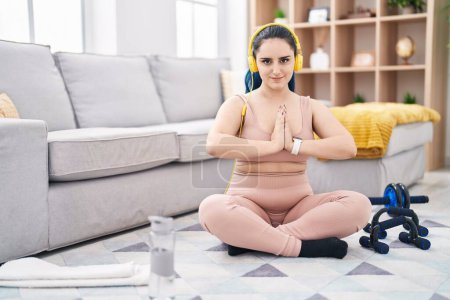 Téléchargez les photos : Young caucasian woman listening to music doing yoga exercise at home - en image libre de droit