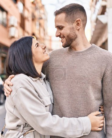 Foto de Hombre y mujer pareja sonriendo confiados abrazándose de pie en la calle - Imagen libre de derechos