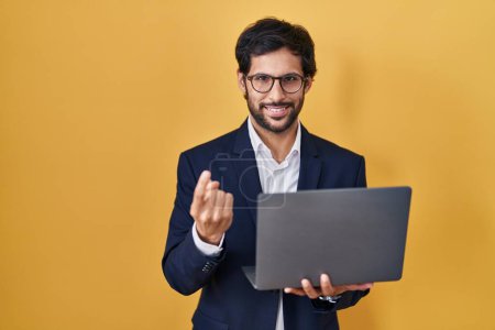 Photo for Handsome latin man working using computer laptop beckoning come here gesture with hand inviting welcoming happy and smiling - Royalty Free Image