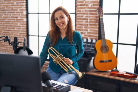 Foto de Young woman musician holding trumpet at music studio - Imagen libre de derechos