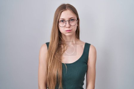 Téléchargez les photos : Young caucasian woman standing over white background puffing cheeks with funny face. mouth inflated with air, crazy expression. - en image libre de droit