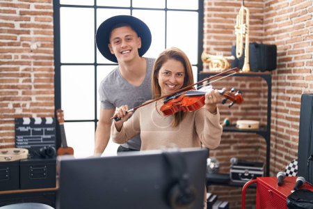 Téléchargez les photos : Man and woman musicians playing violin at music studio - en image libre de droit
