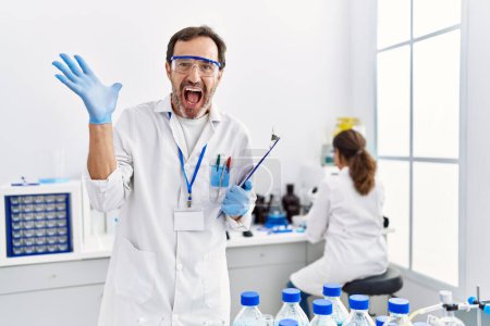 Téléchargez les photos : Homme du Moyen Age travaillant au laboratoire scientifique célébrant la victoire avec un sourire heureux et l'expression gagnante avec les mains levées - en image libre de droit