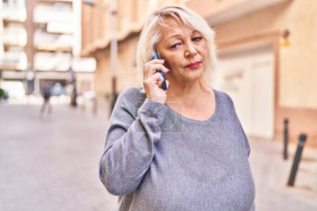 Téléchargez les photos : Moyen Age femme blonde parler sur le smartphone à la rue - en image libre de droit