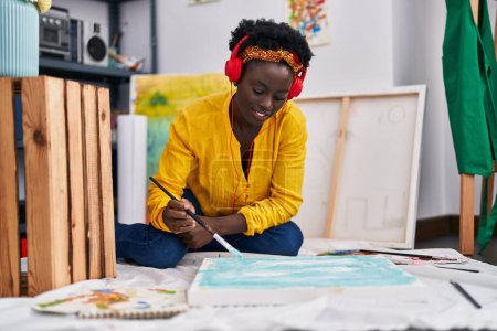 Téléchargez les photos : Young african american woman artist listening music drawing at art studio - en image libre de droit