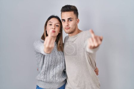 Foto de Young hispanic couple standing over white background showing middle finger, impolite and rude fuck off expression - Imagen libre de derechos