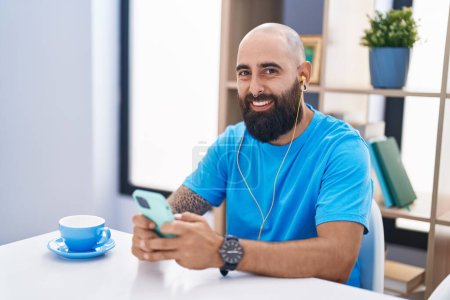 Téléchargez les photos : Young bald man listening to music sitting on table at home - en image libre de droit