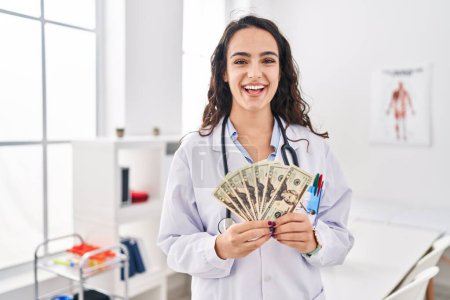 Téléchargez les photos : Young doctor woman holding money smiling and laughing hard out loud because funny crazy joke. - en image libre de droit