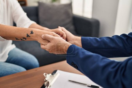 Photo for Middle age man and woman pshychologist and patient consueling holding hands at psychology center - Royalty Free Image