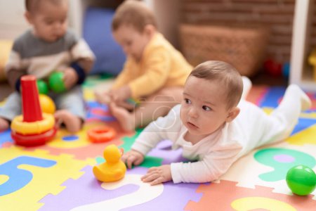 Foto de Grupo de niños pequeños jugando con juguetes sentados en el suelo en el jardín de infantes - Imagen libre de derechos