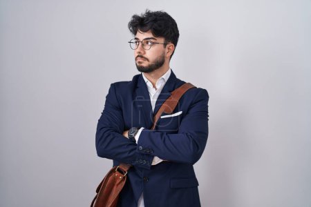 Téléchargez les photos : Homme hispanique avec barbe portant des vêtements de travail regardant sur le côté avec les bras croisés convaincu et confiant - en image libre de droit