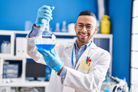 Téléchargez les photos : Homme scientifique afro-américain souriant confiant tenant le tube à essai au laboratoire - en image libre de droit