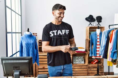 Téléchargez les photos : Handsome hispanic man working as shop assistance taking card payment at retail shop - en image libre de droit