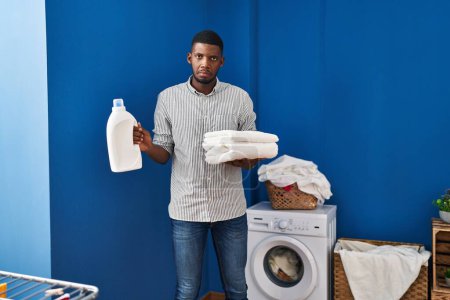 Foto de African american man holding clean towels depressed and worry for distress, crying angry and afraid. sad expression. - Imagen libre de derechos