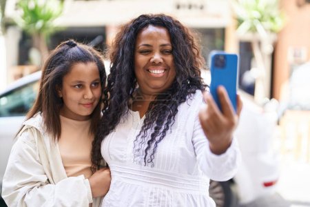 Foto de Madre e hija abrazándose hacen selfie por teléfono inteligente en la calle - Imagen libre de derechos