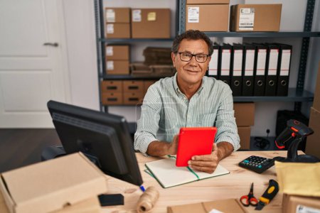 Téléchargez les photos : Middle age man ecommerce business worker using touchpad at office - en image libre de droit